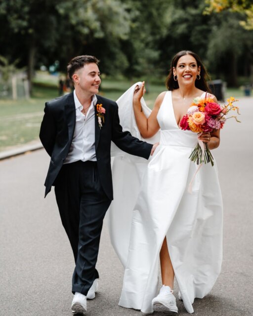 Jess first heard Paddy's voice on the phone in 2019. She'd been organizing a Trans Awareness Week panel and needed a nonbinary speaker from the industry. Someone mentioned Paddy Paddison. They emailed, talked logistics, and Paddy sent through a headshot for the event poster. Jess looked at it and thought, well, this just got complicated.

They never met at that event - Jess couldn't make it. But months later, early 2020, Paddy's face showed up on Tinder. Jess sent a message. A few days later they were meeting for their first date in Victoria Park.

Five years later, they got married at Hackney Town Hall. Both of them had wanted to marry there before they'd even met each other - the palm trees, the big steps out front, the fact that it was home. They'd lived together in Hackney since the beginning.

The week before the wedding, they found out a section of the legal ceremony required gendered language to be read aloud to everyone. There's no gender-neutral option for that part in the UK - it's what makes the ceremony legally binding. They discussed cancelling. Then their registrar Lynn stepped in and found a way to make it work without using gendered language for Paddy.

Jess was nervous about dress shopping. She'd had a difficult relationship with her body and worried the whole experience might feel hard. Sara at Morgan Davies made it safe. The first dress Jess tried on was the one. She tried others just to be sure, but kept coming back to the first.

Paddy ordered suits from ASOS to try on at home - less pressure, more control. Found one they loved, made alterations to the jacket so it fit right.

The day itself was sunny after weeks of rain. Red mustang. Photos in Victoria Park at the exact spot where they'd had their first kiss years earlier. Tacos at the reception. "I Feel Love" by Donna Summer when they walked into the venue, then their first dance to Sister Sledge before the whole room joined in for George Michael.

This one has been featured over on the blog. 

Featured in @dancingwiththem 
Photography by @charliebritzphotography