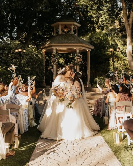 McKenna (she/her) and Meagan (she/her) started with shared playlists and a lot of flights between Texas and Vegas before finally closing the distance ✈️ those that have a long distance relationship under their belt will understand how good that woulda felt!

For their wedding, they wanted a formal spring garden vibe at The Wright House that felt less like Arizona and more like the "Twilight" prom scene - gazebo and all.

They’re both writers, so they skipped the generic ceremony scripts and wrote the whole thing themselves. It was small, and intentional. 

And, they had a rubber chicken toss in place of a bouquet toss to win a Raising Cane’s gift card - which we just think is fun! 

Meagan walked down the aisle with her Tia and Nana, McKenna’s dad officiated. The reception entrance was to "Only Angel" by Harry Styles that matched their energy perfectly. 

They also prioritized working with LGBTQ+ owned vendors like @adrianamayaphotography, which they said made them feel completely seen through the whole "bridal era." 🌈 

You'll find this one over on the blog to lust over ☝️ 

Featured in @dancingwithher
Photography by @adrianamayaphotography
Lovers @meagan.v.apodaca & @kenna_apodaca

Cake @cakebykenna
DJ @djfloentertainment
Dress @truesociety_phoenix by @missstellayork & @luvbridal
Florist @cactusbloomfloral
Hair & Makeup @bellabridalbeauty
Rings @brilliantearth
Seamstress @theheartcenteredseamstress
Stationery @minted
Venue @wrighthouseweddings
